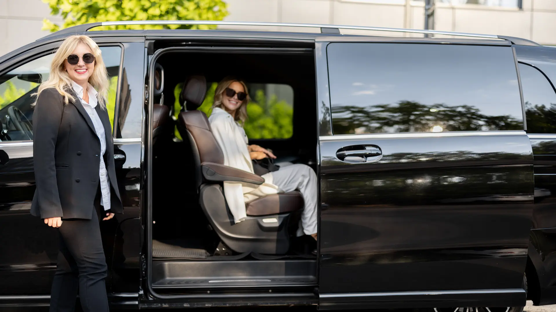 Illustrative stock photograph of two women beside and inside a black passenger minivan; not Foundation participants or a Foundation vehicle