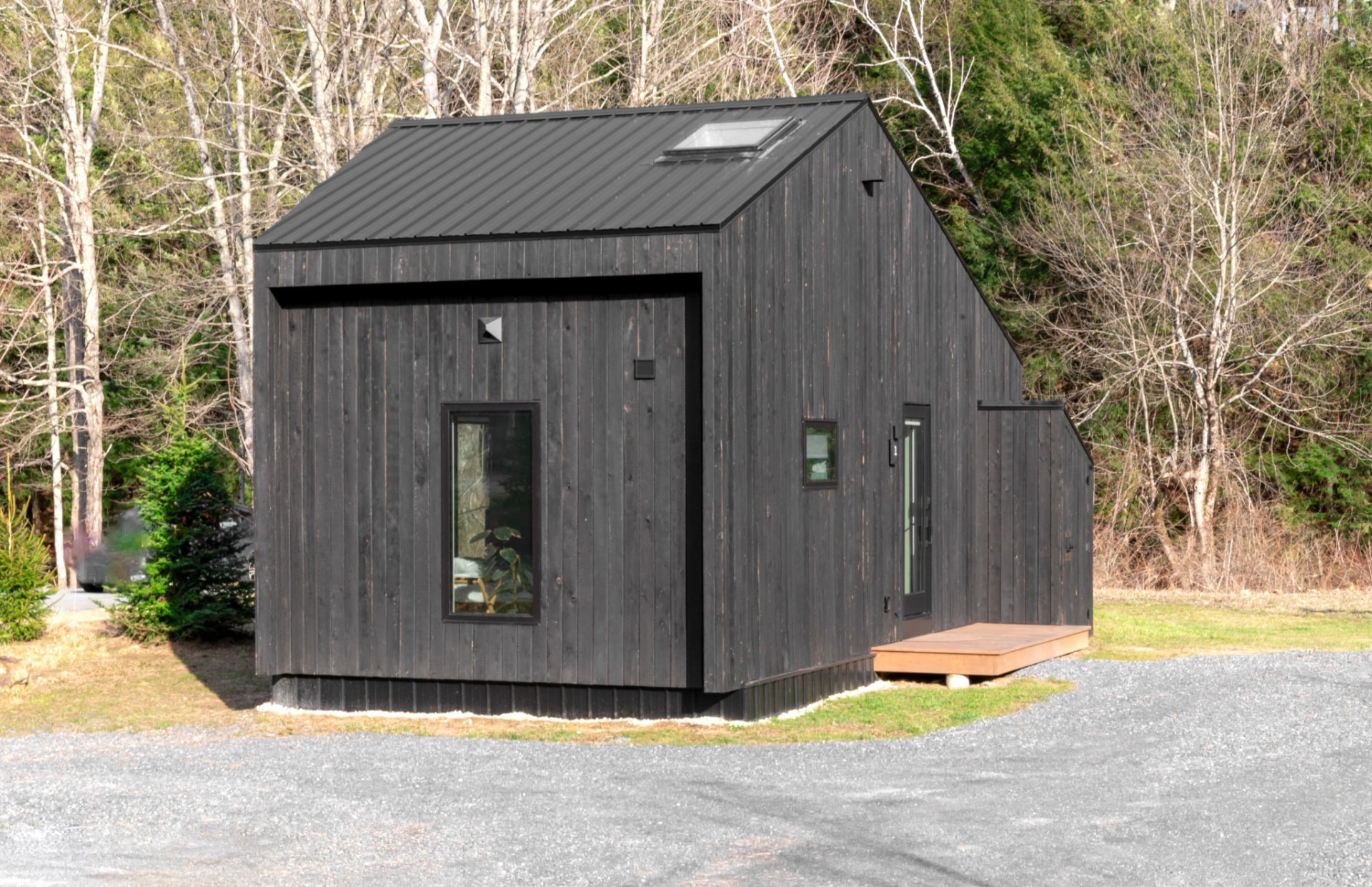 Approved photograph of a small dark wood-clad cottage surrounded by trees, illustrating the future residential style envisioned; not Foundation-owned property